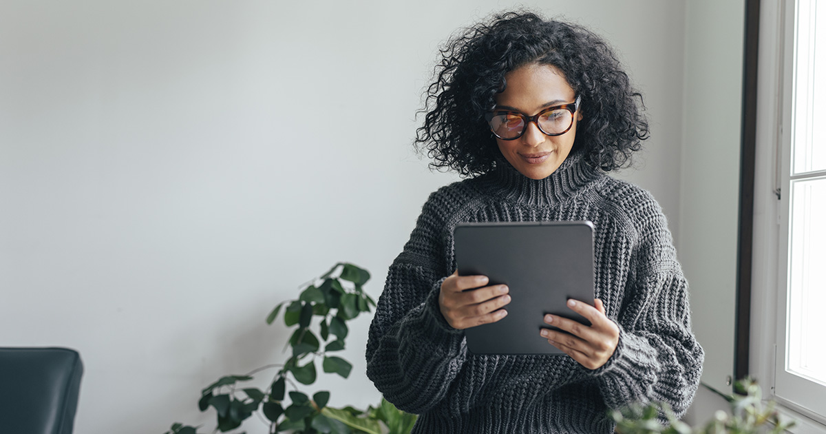 femme métis, trentaine, cheveux noir frisés, tenant une tablette d'ordinateur dans ses mains